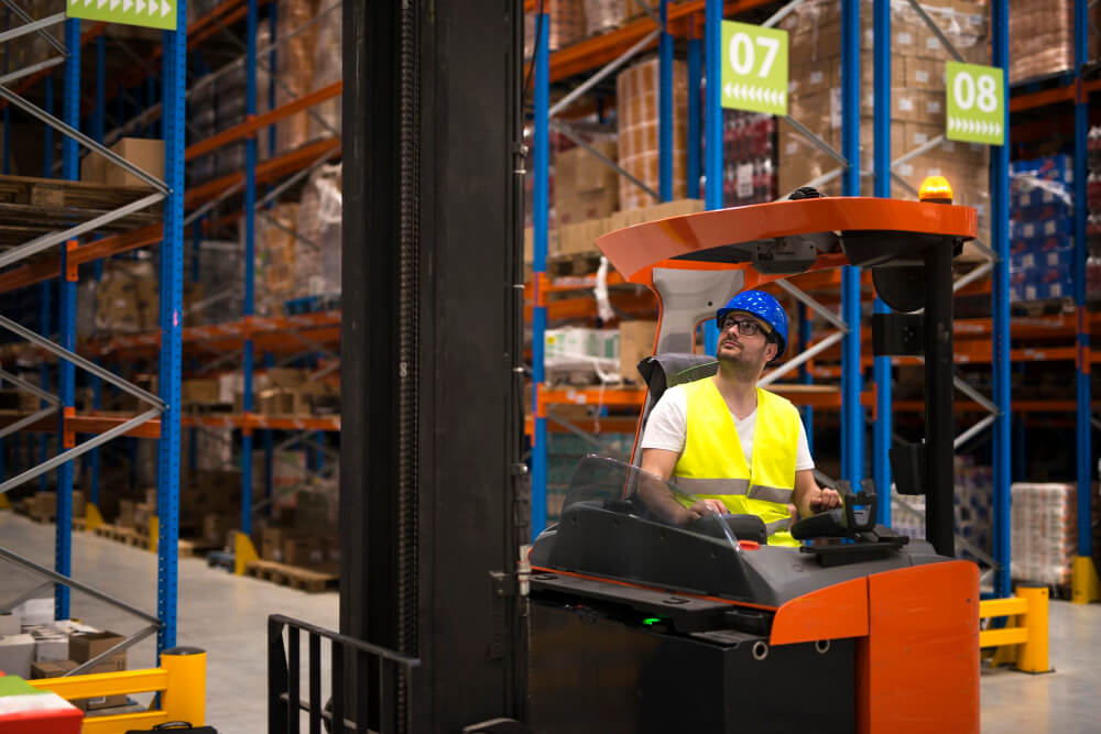 forklift driver relocating and lifting goods in large warehouse center1